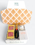 Gift box with shell pattern, containing a bottle of Moët & Chandon, a box of chocolates, and a candle, branded 'YUTI'.